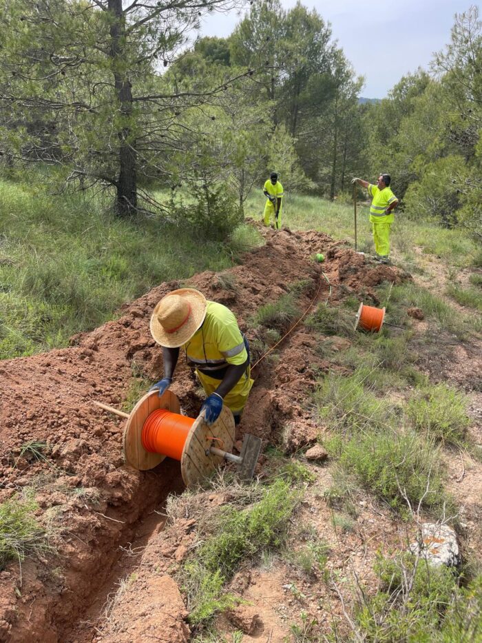 Vista del cable de fibra óptica junto con el cable guía de acero instalado en una zanja rural.